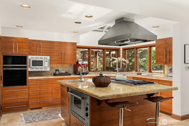 3103 Mount Rainier Dr S, Seattle, WA 98144 - kitchen featuring stainless steel appliances, island range hood, brown cabinetry, an island with sink, and backsplash