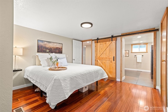 407 Leber St NE, Orting, WA 98360 - bedroom with a barn door, hardwood / wood-style floors, and ensuite bath