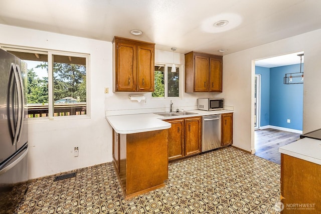 6808 NE 165th St, Kenmore, WA 98028 - kitchen with appliances with stainless steel finishes, brown cabinetry, light countertops, and healthy amount of natural light