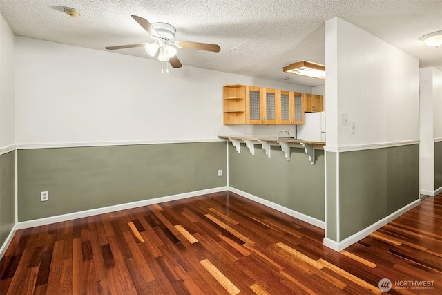 2506 S 317th St Unit 103, Federal Way, WA 98003 - kitchen featuring freestanding refrigerator, wood finished floors, a kitchen bar, a ceiling fan, and glass insert cabinets