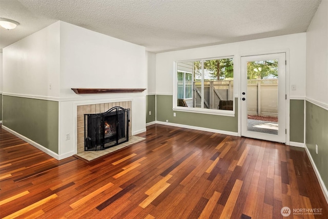 2506 S 317th St Unit 103, Federal Way, WA 98003 - unfurnished living room featuring wood finished floors, a tile fireplace, and a textured ceiling