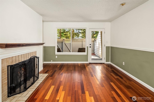 2506 S 317th St Unit 103, Federal Way, WA 98003 - unfurnished living room featuring hardwood / wood-style flooring, a textured ceiling, and a tile fireplace