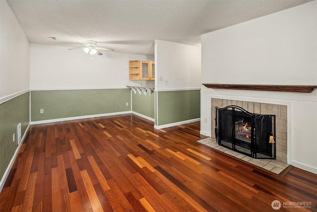2506 S 317th St Unit 103, Federal Way, WA 98003 - unfurnished living room with a tile fireplace, wood finished floors, ceiling fan, and a textured ceiling