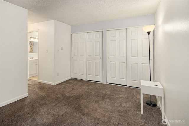 2506 S 317th St Unit 103, Federal Way, WA 98003 - unfurnished bedroom with multiple closets, carpet flooring, and a textured ceiling