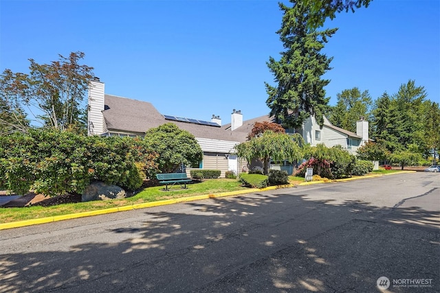 2506 S 317th St Unit 103, Federal Way, WA 98003 - obstructed view of property with roof mounted solar panels and a chimney