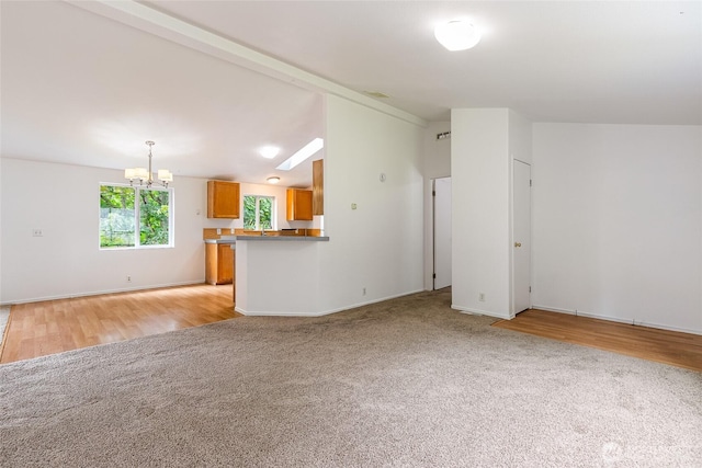 370 Van Wyck Rd, Bellingham, WA 98226 - unfurnished living room featuring a chandelier, light carpet, light wood-style flooring, and lofted ceiling