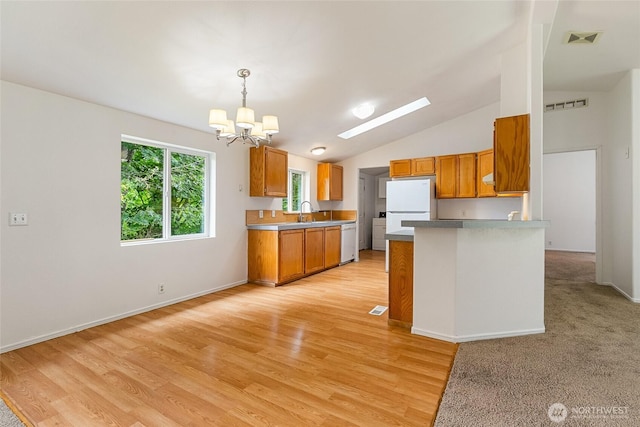 370 Van Wyck Rd, Bellingham, WA 98226 - kitchen featuring white appliances, a chandelier, brown cabinets, light wood-type flooring, and a peninsula
