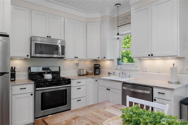 17 Beach Cabin Ln, Pacific Beach, WA 98571 - kitchen with stainless steel appliances, light countertops, white cabinets, hanging light fixtures, and crown molding