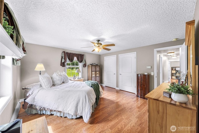 599 Loomis Trail Rd, Lynden, WA 98264 - bedroom featuring multiple closets, light wood-style floors, ceiling fan, a textured ceiling, and a baseboard heating unit