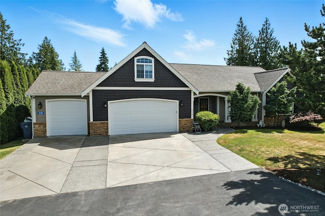 218 Lilly Ln, Mount Vernon, WA 98274 - craftsman-style home featuring concrete driveway, stone siding, an attached garage, a front yard, and a shingled roof