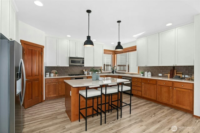 3419 NE Meadow Way, Issaquah, WA 98029 - kitchen with appliances with stainless steel finishes, light wood finished floors, backsplash, a breakfast bar area, and recessed lighting