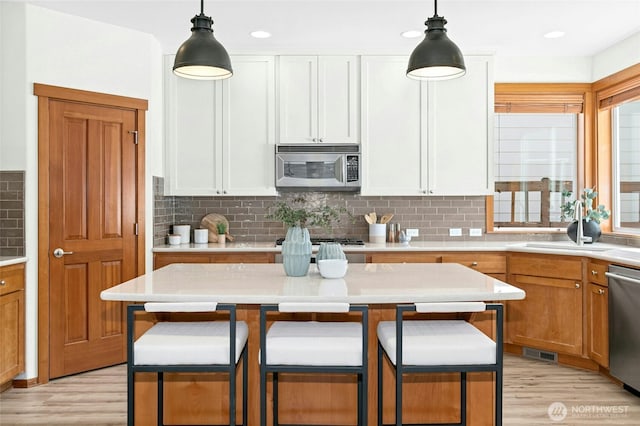 3419 NE Meadow Way, Issaquah, WA 98029 - kitchen featuring stainless steel appliances, light wood-type flooring, a breakfast bar area, light countertops, and recessed lighting