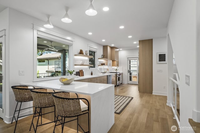 4043 55th Ave SW, Seattle, WA 98116 - kitchen with open shelves, light countertops, high end stove, a kitchen bar, and a peninsula