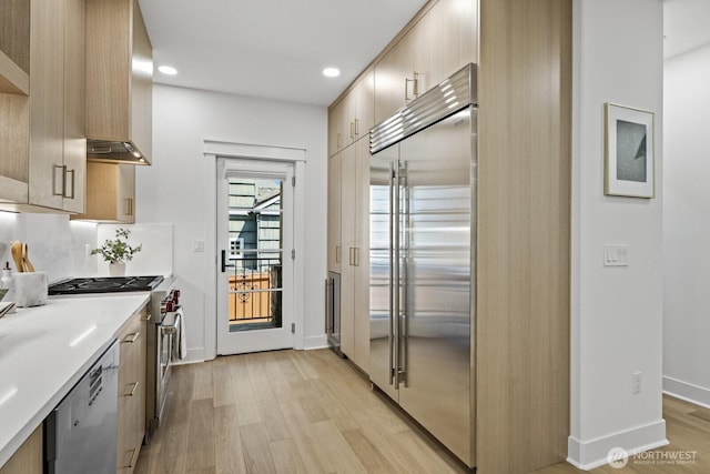 4043 55th Ave SW, Seattle, WA 98116 - kitchen with high end appliances, light wood finished floors, modern cabinets, light countertops, and wall chimney exhaust hood