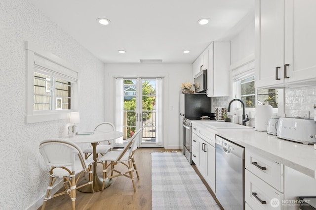 4043 55th Ave SW, Seattle, WA 98116 - kitchen with appliances with stainless steel finishes, light wood finished floors, white cabinetry, recessed lighting, and decorative backsplash