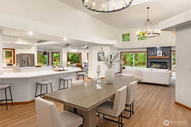 12407 Upper Preston Rd SE, Issaquah, WA 98027 - dining area with a chandelier, light wood-type flooring, plenty of natural light, a high ceiling, and a stone fireplace
