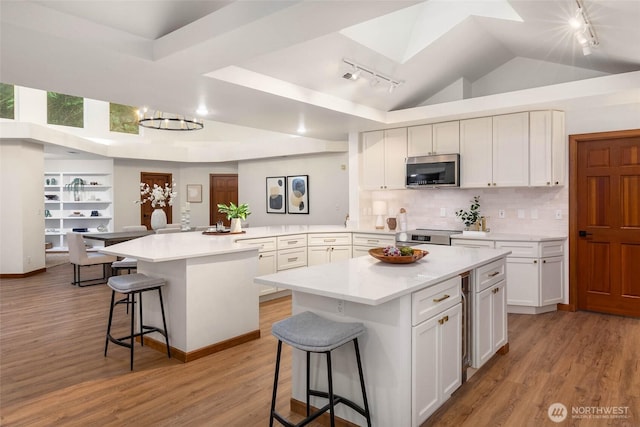 12407 Upper Preston Rd SE, Issaquah, WA 98027 - kitchen featuring stainless steel appliances, track lighting, a peninsula, a breakfast bar, and vaulted ceiling