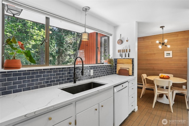 10765 Burke Ave N Unit 14, Seattle, WA 98133 - kitchen featuring white dishwasher, decorative backsplash, wooden walls, white cabinets, and pendant lighting