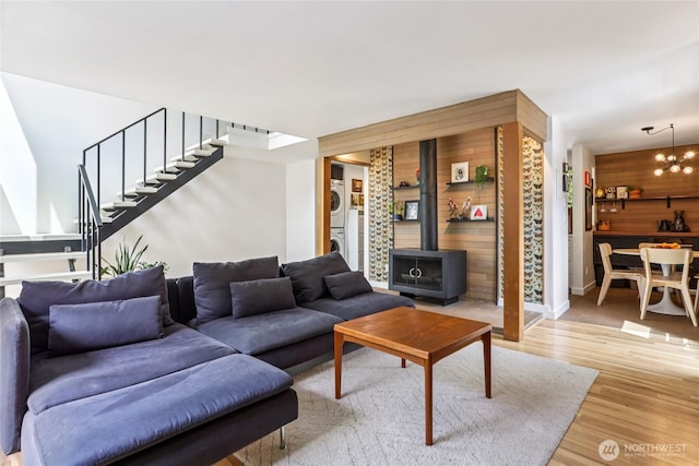 10765 Burke Ave N Unit 14, Seattle, WA 98133 - living room featuring stacked washing machine and dryer, a wood stove, stairs, light wood-style floors, and a chandelier