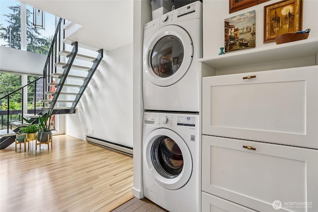 10765 Burke Ave N Unit 14, Seattle, WA 98133 - laundry room featuring stacked washer / dryer, baseboard heating, light wood-style flooring, and cabinet space