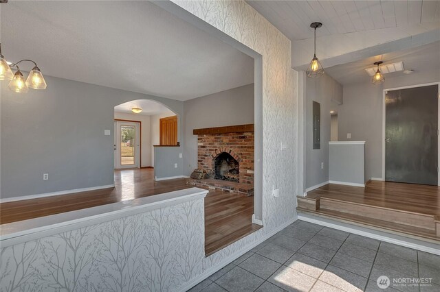 622 119th Ave E, Edgewood, WA 98372 - unfurnished living room featuring tile patterned floors, arched walkways, electric panel, a fireplace, and a chandelier