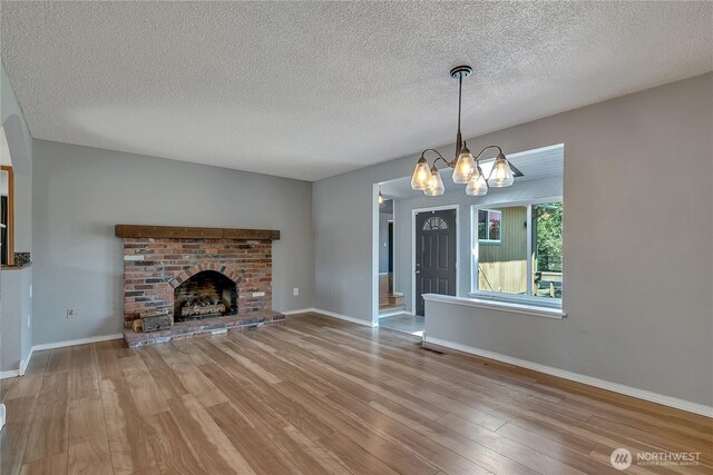 622 119th Ave E, Edgewood, WA 98372 - unfurnished living room featuring wood finished floors, a textured ceiling, a chandelier, and a fireplace