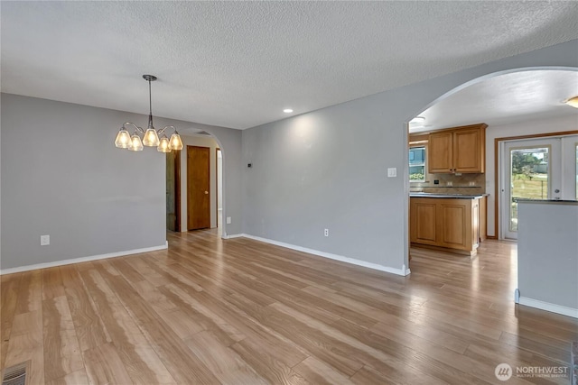 622 119th Ave E, Edgewood, WA 98372 - unfurnished living room featuring arched walkways, a textured ceiling, light wood finished floors, a chandelier, and recessed lighting