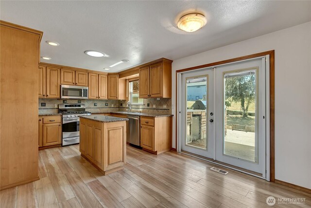 622 119th Ave E, Edgewood, WA 98372 - kitchen with stainless steel appliances, decorative backsplash, french doors, dark stone countertops, and light wood-style flooring