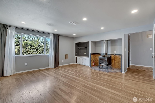 622 119th Ave E, Edgewood, WA 98372 - unfurnished living room with light wood-type flooring, a wood stove, and recessed lighting