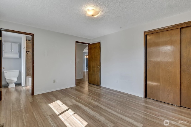 622 119th Ave E, Edgewood, WA 98372 - unfurnished bedroom featuring light wood-style flooring, a closet, a textured ceiling, and ensuite bath