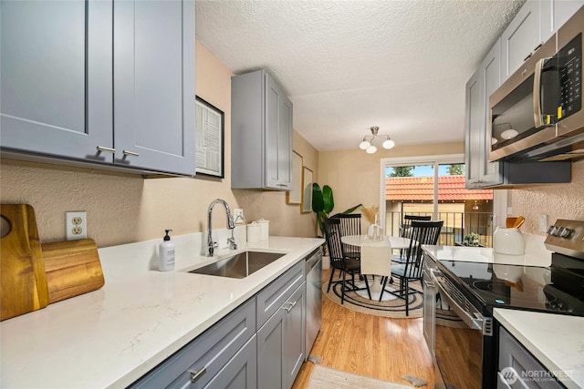 15749 NE 18th St Unit B5, Bellevue, WA 98008 - kitchen featuring appliances with stainless steel finishes, gray cabinetry, light wood-style flooring, a textured ceiling, and a chandelier