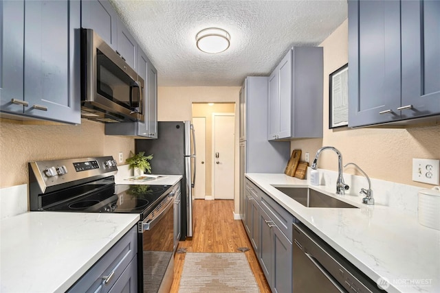 15749 NE 18th St Unit B5, Bellevue, WA 98008 - kitchen with appliances with stainless steel finishes, light wood-style floors, a textured ceiling, light stone countertops, and gray cabinets
