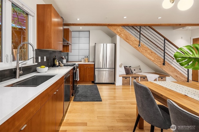 3659 Whitman Ave N, Seattle, WA 98103 - kitchen featuring stainless steel appliances, brown cabinets, light countertops, light wood finished floors, and decorative backsplash