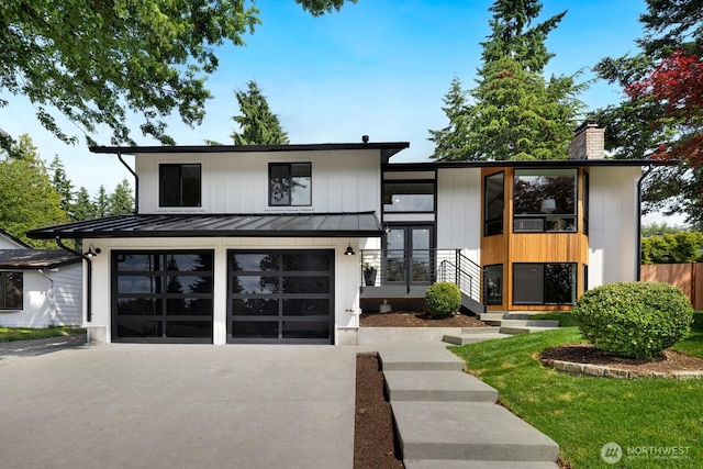 7502 117th Ave NE, Kirkland, WA 98033 - view of front of house featuring a standing seam roof, driveway, a chimney, a garage, and a metal roof
