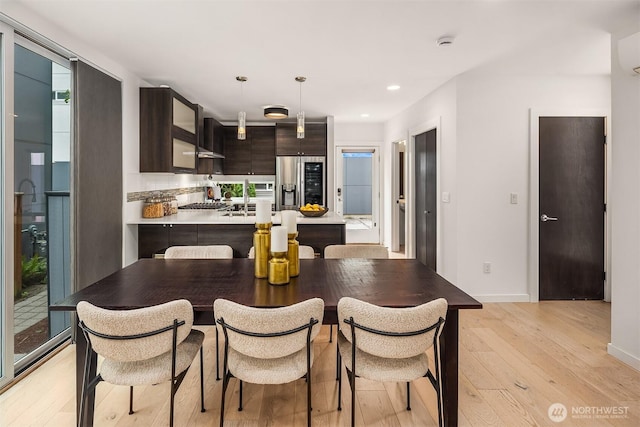 909 29th Ave S, Seattle, WA 98144 - kitchen featuring stainless steel fridge with ice dispenser, light wood-type flooring, dark brown cabinets, light countertops, and a peninsula
