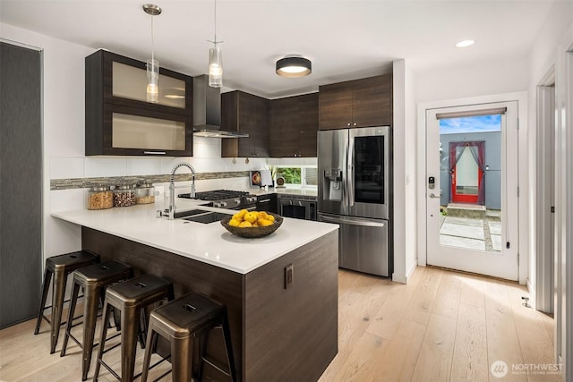 909 29th Ave S, Seattle, WA 98144 - kitchen featuring stainless steel fridge with ice dispenser, wall chimney range hood, dark brown cabinets, a breakfast bar, and light countertops