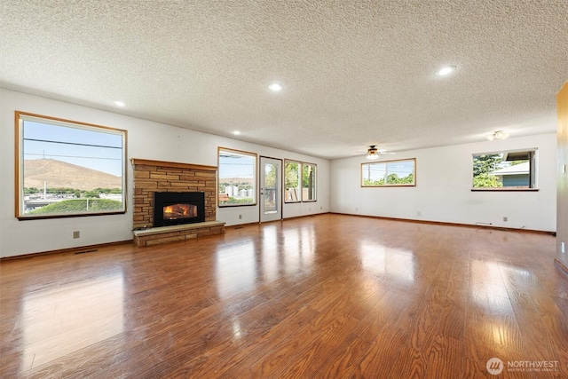 103 Crest Dr, Ephrata, WA 98823 - unfurnished living room with a textured ceiling, a ceiling fan, wood finished floors, recessed lighting, and a fireplace