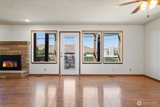 103 Crest Dr, Ephrata, WA 98823 - unfurnished living room featuring a textured ceiling, wood finished floors, plenty of natural light, and a fireplace