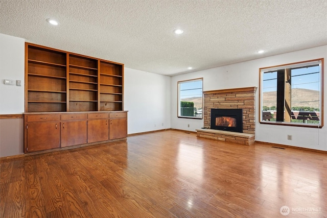 103 Crest Dr, Ephrata, WA 98823 - unfurnished living room with a textured ceiling, wood finished floors, a stone fireplace, and recessed lighting