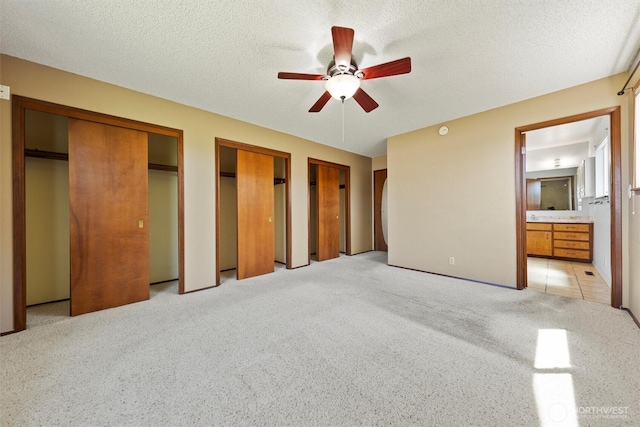 103 Crest Dr, Ephrata, WA 98823 - unfurnished bedroom with two closets, light colored carpet, connected bathroom, ceiling fan, and a textured ceiling