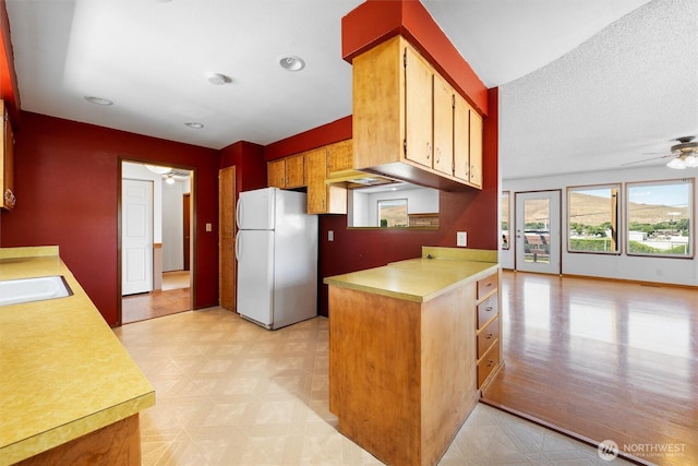 103 Crest Dr, Ephrata, WA 98823 - kitchen with freestanding refrigerator, light flooring, light countertops, ceiling fan, and a peninsula