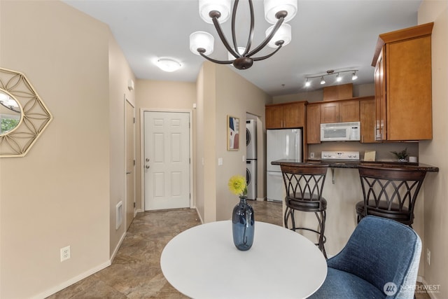 6125 Kennedy Ave SE Unit F7, Auburn, WA 98092 - kitchen featuring white appliances, estacked washer and dryer, dark countertops, a chandelier, and a peninsula