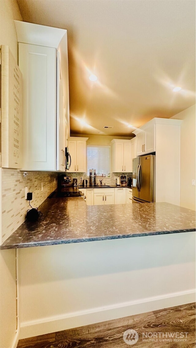 23884 NE 112th Cir Unit 2, Redmond, WA 98053 - kitchen with stainless steel appliances, a peninsula, backsplash, dark stone counters, and white cabinetry