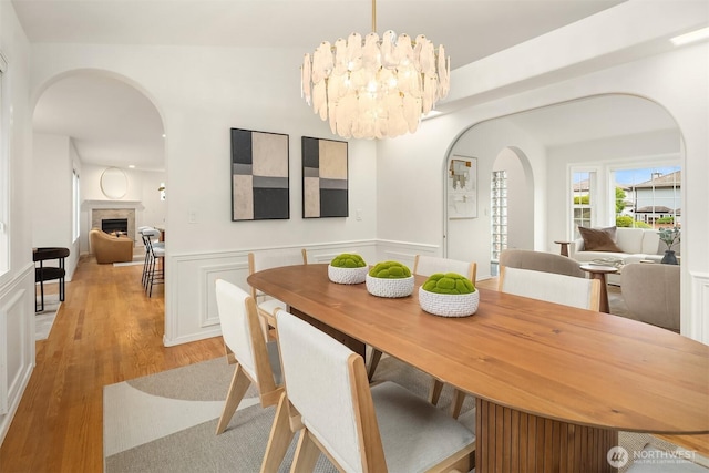 1417 232nd Pl SW, Bothell, WA 98021 - dining area with arched walkways, light wood-style floors, wainscoting, a fireplace, and a chandelier