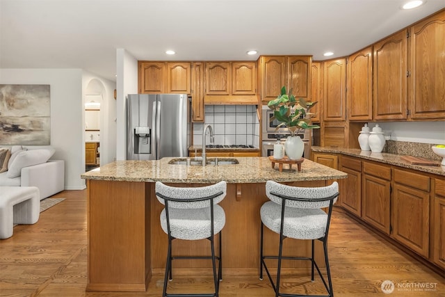 1417 232nd Pl SW, Bothell, WA 98021 - kitchen featuring stainless steel appliances, an island with sink, light stone counters, recessed lighting, and brown cabinetry