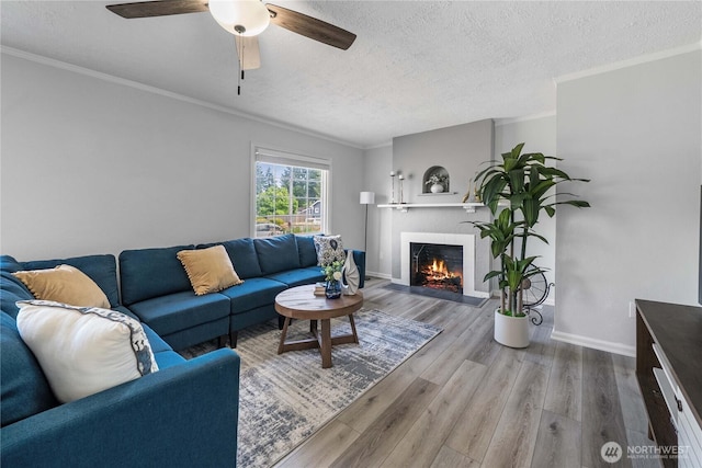 4840 E B St, Tacoma, WA 98404 - living area featuring a textured ceiling, a lit fireplace, ornamental molding, wood finished floors, and a ceiling fan