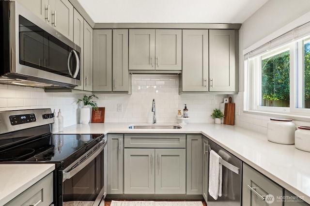 3923 NE 22nd Pl, Renton, WA 98056 - kitchen featuring stainless steel appliances, gray cabinetry, decorative backsplash, and light countertops