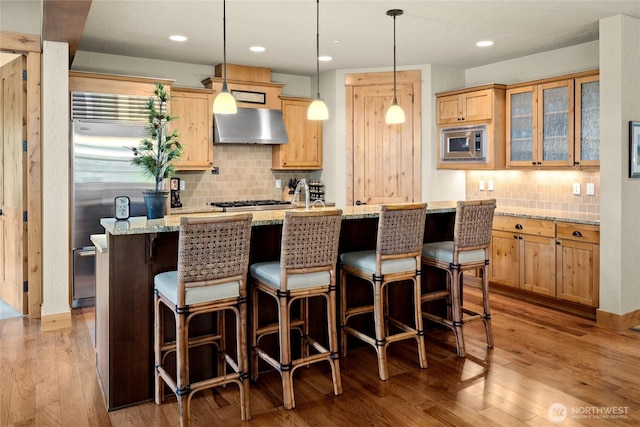 80 Queens Loop, Cle Elum, WA 98922 - kitchen with wall chimney range hood, built in appliances, backsplash, a kitchen island with sink, and light brown cabinets