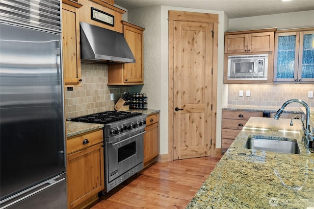 80 Queens Loop, Cle Elum, WA 98922 - kitchen featuring high quality appliances, wall chimney range hood, decorative backsplash, light wood-style floors, and light stone counters