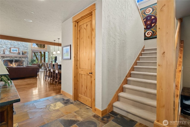 80 Queens Loop, Cle Elum, WA 98922 - stairway featuring stone tile flooring, a textured ceiling, a fireplace, and a textured wall